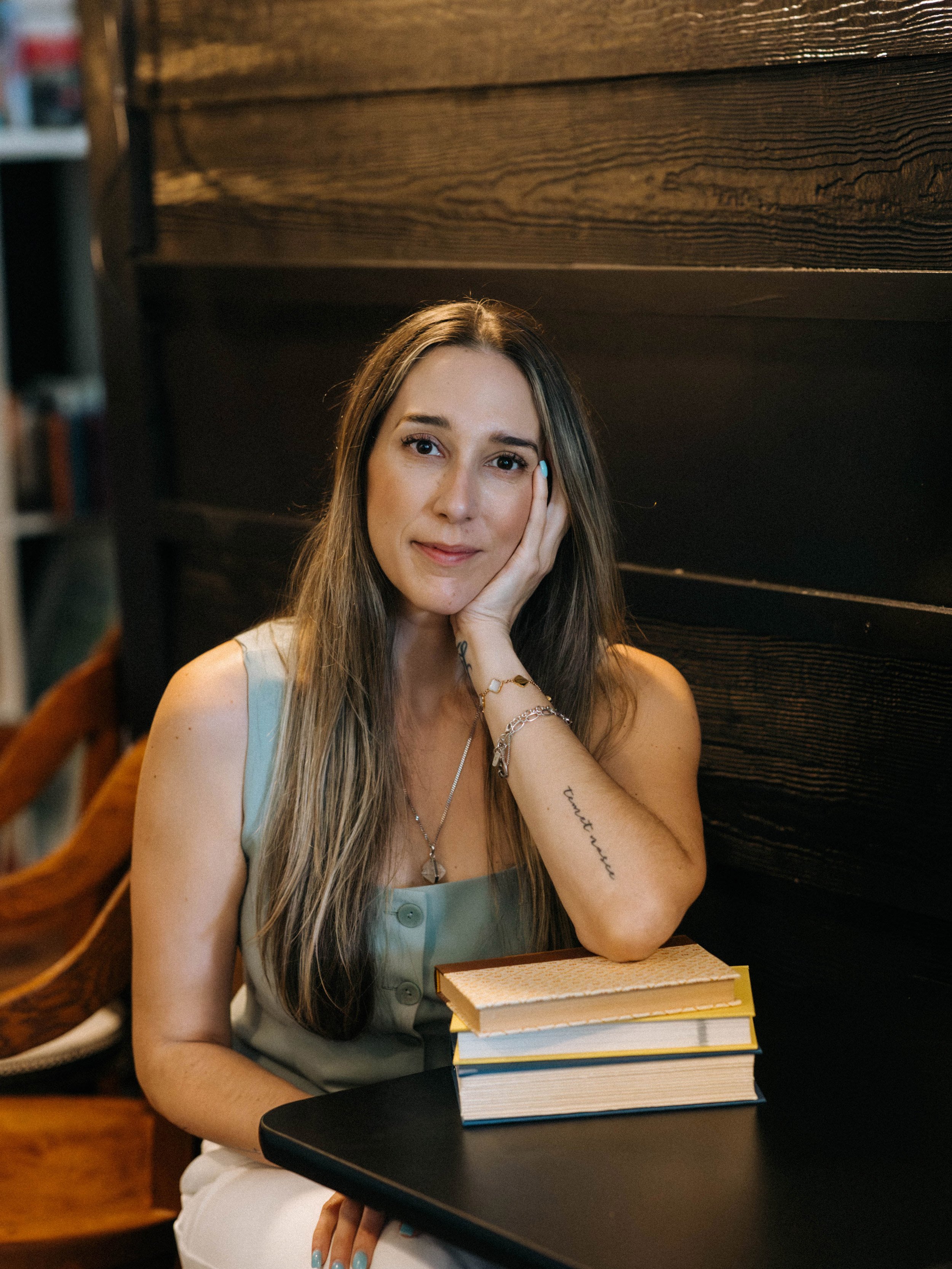 Camila Hurst in a coffee library on a table and surounded by books